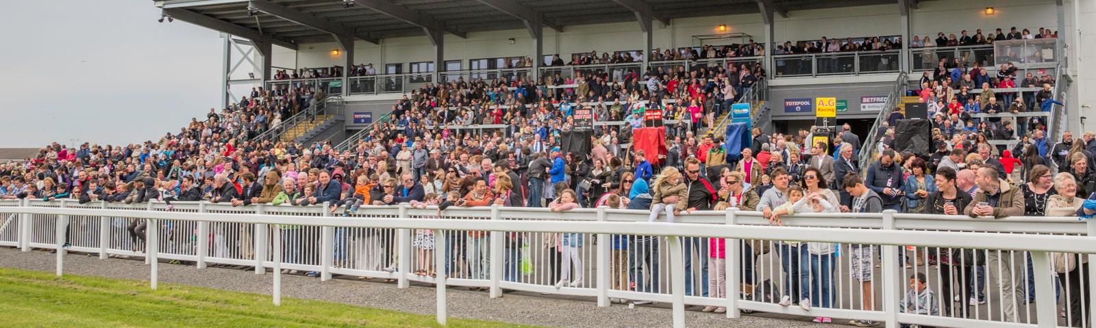 Crowds gathered on the grandstand while at the races.