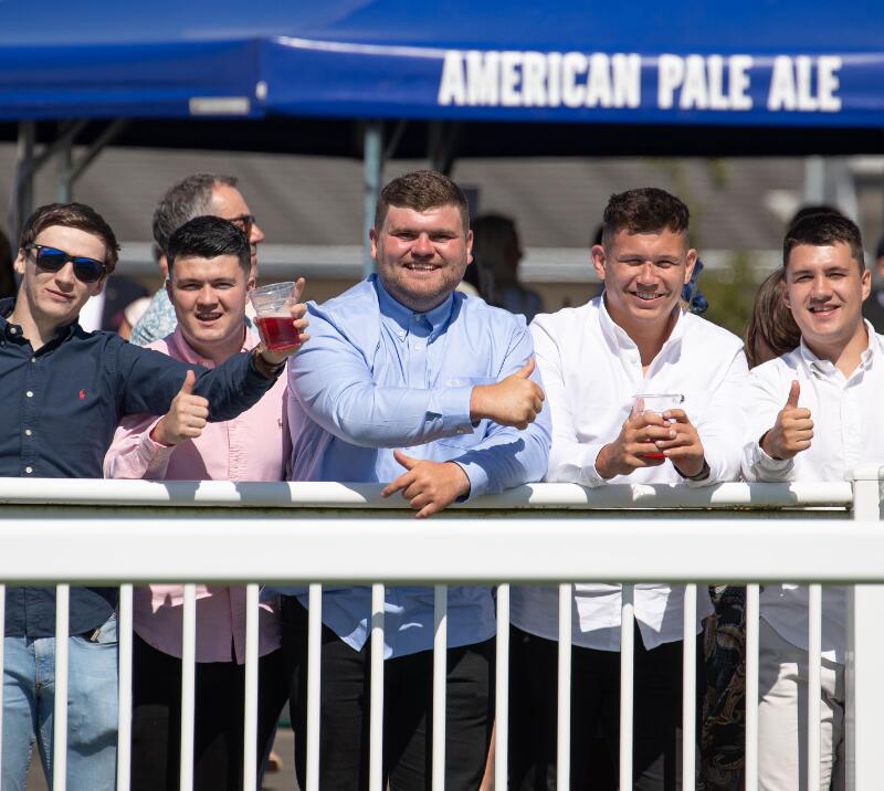 A group of race goers giving a thumbs up at the trackside