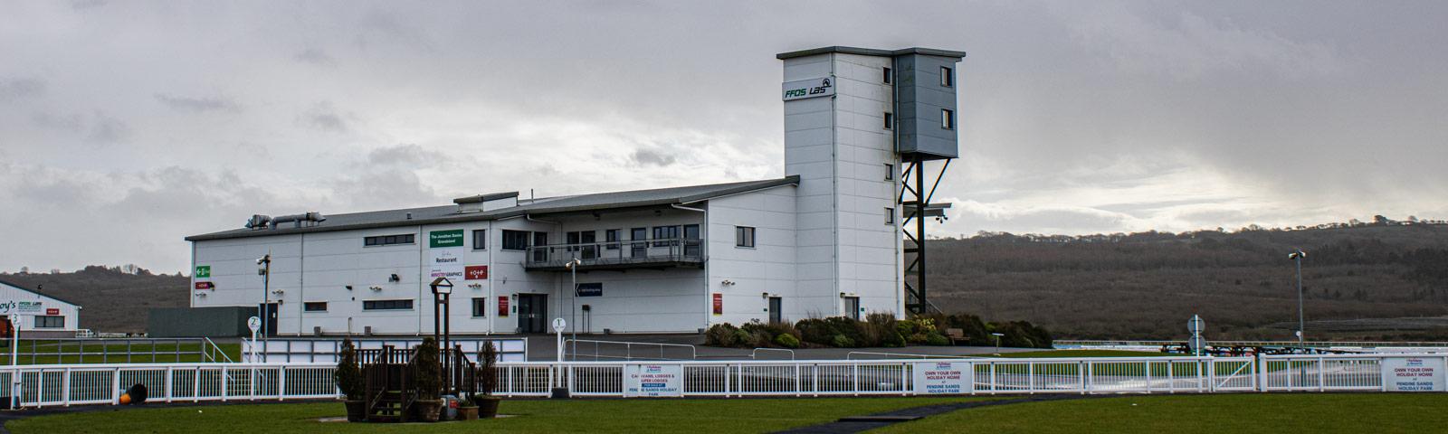The main grandstand building at Ffos Las Racecourse with the parade ring in the foreground.